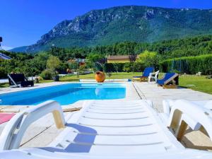 a swimming pool with white lounge chairs and a mountain at Hotel Restaurant Rose des Pyrénées in Belvianes-et-Cavirac