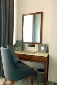 a desk with a mirror and a chair in a room at Parliament Palace Hotel in Khujand