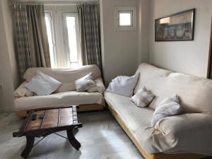 Sala de estar con 2 sofás blancos y mesa de centro en Apartamento Playa La Muralla, en El Puerto de Santa María