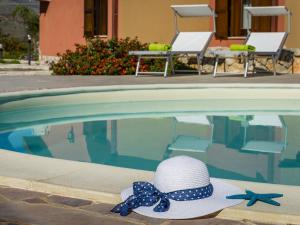 a hat with a bow tie sitting next to a swimming pool at Belvilla by OYO Beautiful Holiday Home near Beach in Castellammare del Golfo