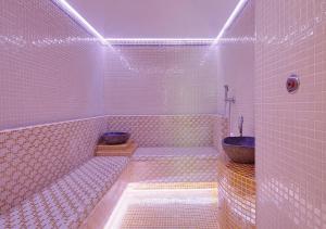 a white tiled bathroom with a tub and a sink at Monastero Di Cortona Hotel & Spa in Cortona
