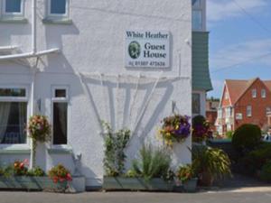 a white building with a sign for a guest house at White Heather Guest House in Mablethorpe