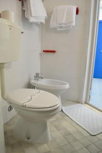 een witte badkamer met een toilet en een wastafel bij Hotel Playa e Mare Nostrum in Caorle