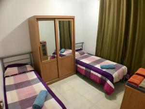 Cette petite chambre comprend 2 lits et un miroir. dans l'établissement Merhba Apartment, à San Pawl il-Baħar