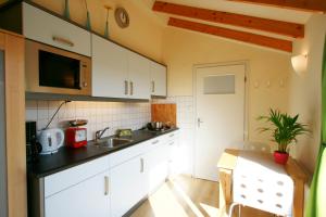 een keuken met witte kasten, een wastafel en een tafel bij DO27 Charmante Studio in Domburg in Domburg