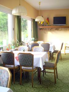 a dining room with tables and chairs and a television at Hotel Haus Hellhohl Garni in Brilon