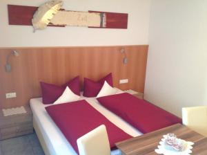 a bedroom with a bed with red pillows and a table at Apart Garni Lais in Galtür