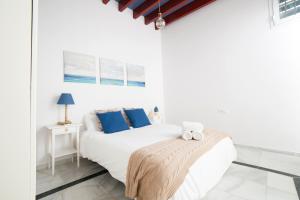 a white bedroom with a bed with blue pillows at AlohaMundi Bailén in Seville