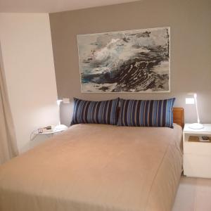 Un dormitorio con una cama con una pintura encima. en Ocean Flat en Río de Janeiro