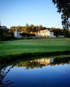 een huis op een golfbaan met een reflectie in het water bij Château d'Hodebert in Saint-Paterne-Racan