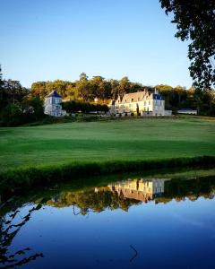 una casa en un campo de golf con un reflejo en el agua en Château d'Hodebert en Saint-Paterne-Racan