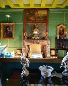 een groene kamer met een open haard en portretten aan de muur bij Château d'Hodebert in Saint-Paterne-Racan