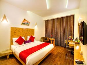 a hotel room with a bed and a desk and a television at Hotel Rockdale in Visakhapatnam