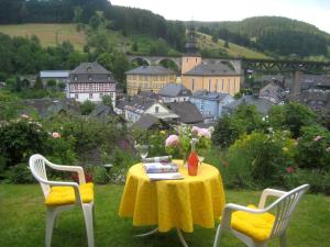 einen Tisch mit einem gelben Tischtuch und zwei Stühlen in der Unterkunft Ferienwohnung Haus am Sommerberg in Ludwigsstadt