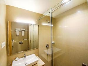 a bathroom with a sink and a shower with a mirror at Hotel Rockdale in Visakhapatnam