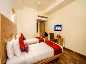 a hotel room with two beds and a television at Hotel Rockdale in Visakhapatnam