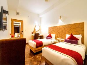 a hotel room with two beds and a chair at Hotel Rockdale in Visakhapatnam
