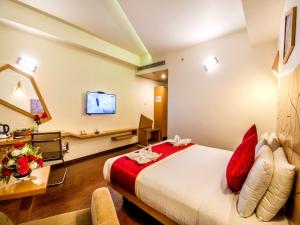 a hotel room with a bed and a desk and a tv at Hotel Rockdale in Visakhapatnam