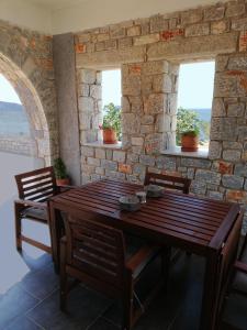 a dining room with a table and chairs and windows at Mezapos Villa Makrina in Mézapos