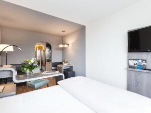 Habitación de hotel con cama y escritorio con espejo. en Living Hotel Kaiser Franz Joseph, en Viena