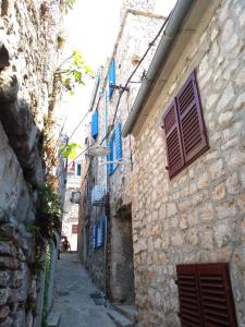 un callejón con persianas azules en un edificio de piedra en Kuća Get en Betina