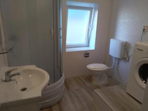baño con lavabo y aseo y ventana en Kuća Get, en Betina