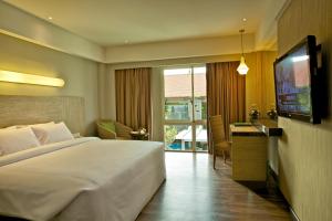 um quarto de hotel com uma cama grande e uma televisão em Bintang Kuta Hotel em Kuta