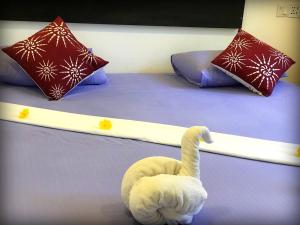 un cigno bianco seduto su un letto con cuscini di Monara Backpacker Inn Unawatuna a Unawatuna