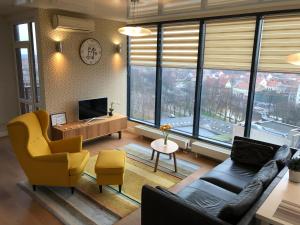 uma sala de estar com um sofá, cadeiras e janelas em Old Town Panorama Apartments em Klaipeda