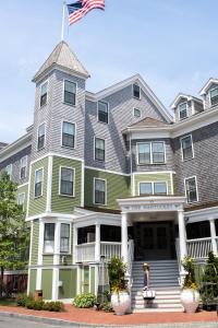 uma mulher caminha em frente a uma casa grande em The Nantucket Hotel & Resort em Nantucket