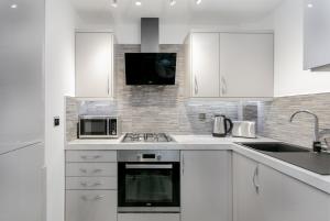 a white kitchen with a sink and a microwave at Forbes Retreat - Donnini Apartments in Ayr