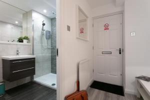 a bathroom with a shower and a white door at Forbes Retreat - Donnini Apartments in Ayr