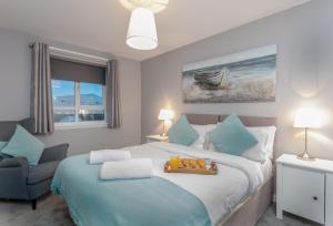 a bedroom with a large bed and a chair at Forbes Retreat - Donnini Apartments in Ayr