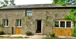a stone house with a dog sitting in the doorway at Glanwye in Hay-on-Wye