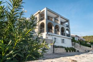 a white house with trees in front of it at Apartments Lavanda in Vinišće