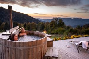 two girls bathing in a hot tub on a deck at Là Haut & Spa in Ventron