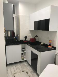 cocina con armarios blancos y encimera negra en VICTORIA LUXURY APARTMENT en Bucarest