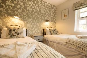 Duas camas num quarto com papel de parede floral em Tissington Cottage- Darwin Lake Holiday Village em Matlock