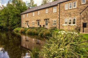 an old brick building next to a river at Tissington Cottage- Darwin Lake Holiday Village in Matlock