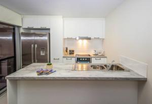 a kitchen with a sink and a stainless steel refrigerator at The Happy Delightful Place - Entire 2 Room Apartment in Cockburn Central