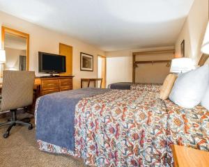 Pokój hotelowy z łóżkiem i biurkiem z telewizorem w obiekcie Rodeway Inn Baker City w mieście Baker City