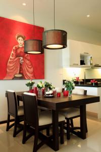 a dining room table with chairs and a painting of a woman at Two Villas Holiday Phuket: Onyx Style Nai Harn Beach in Nai Harn Beach