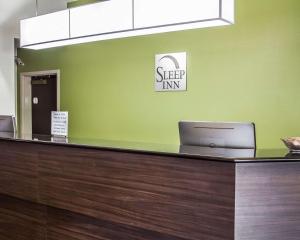 a reception desk with a laptop on a green wall at Sleep Inn & Suites Roseburg North Near Medical Center in Roseburg