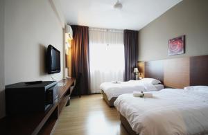 a hotel room with two beds and a flat screen tv at Aroma Hotel in Butterworth