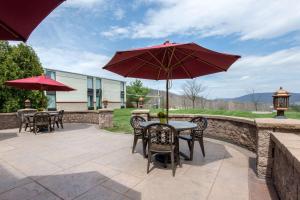 een patio met tafels en stoelen en een parasol bij Quality Inn & Suites in Mansfield