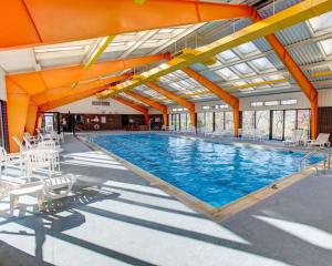 a large swimming pool with white chairs and an orange ceiling at Comfort Inn Conference Center in Churchill
