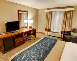Habitación de hotel con cama, escritorio y TV. en Comfort Inn Conference Center, en Churchill