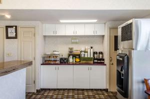 a kitchen with white cabinets and a refrigerator at Rodeway Inn State College - near University in State College