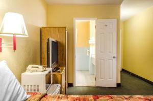 a room with a bed and a television and a door at Relax Inn in Lewisburg