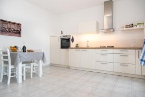 a kitchen with white cabinets and a table with chairs at Apartments Lavanda in Vinišće